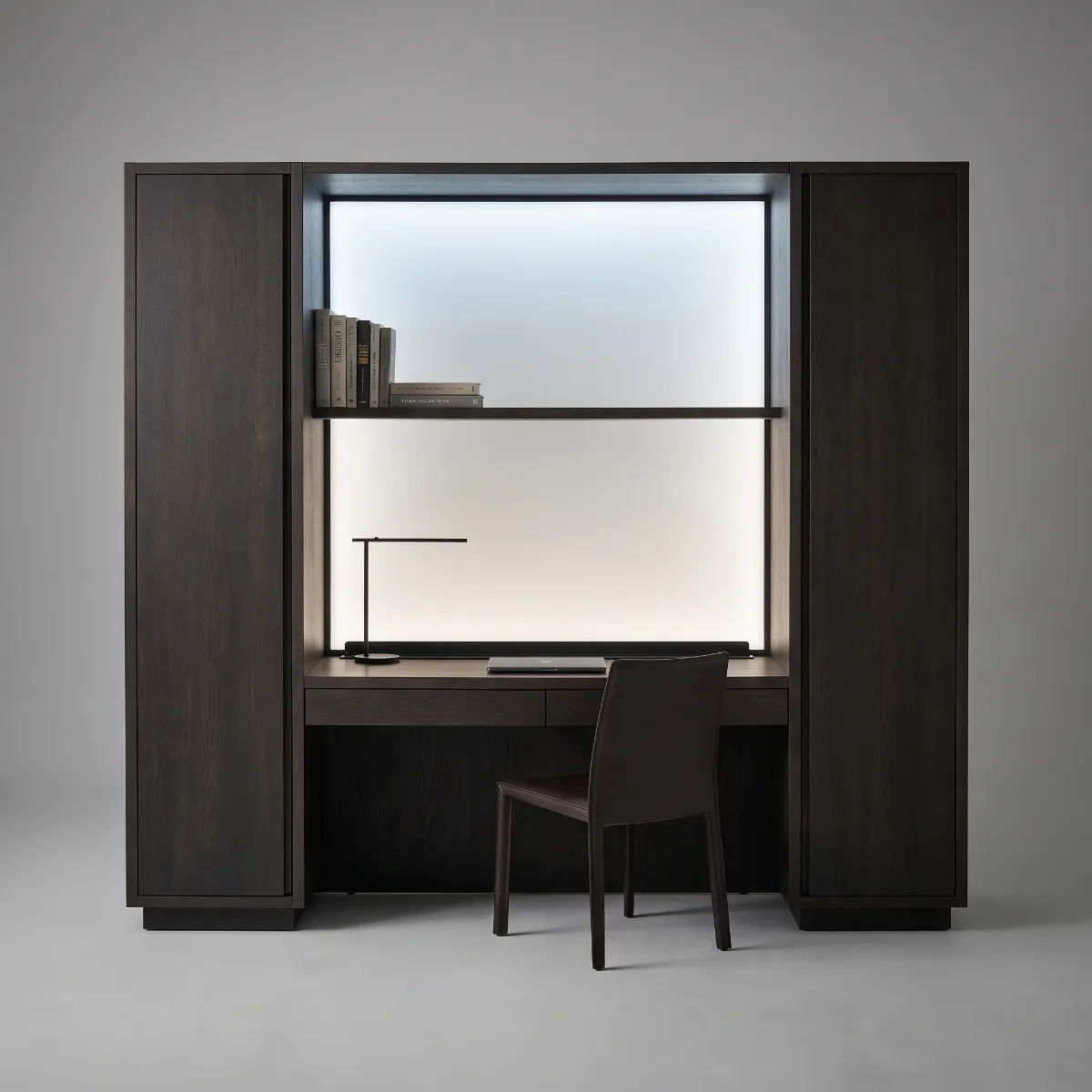 A dark oak study wall with a desk under a daylight-white panel between two tall cupboards