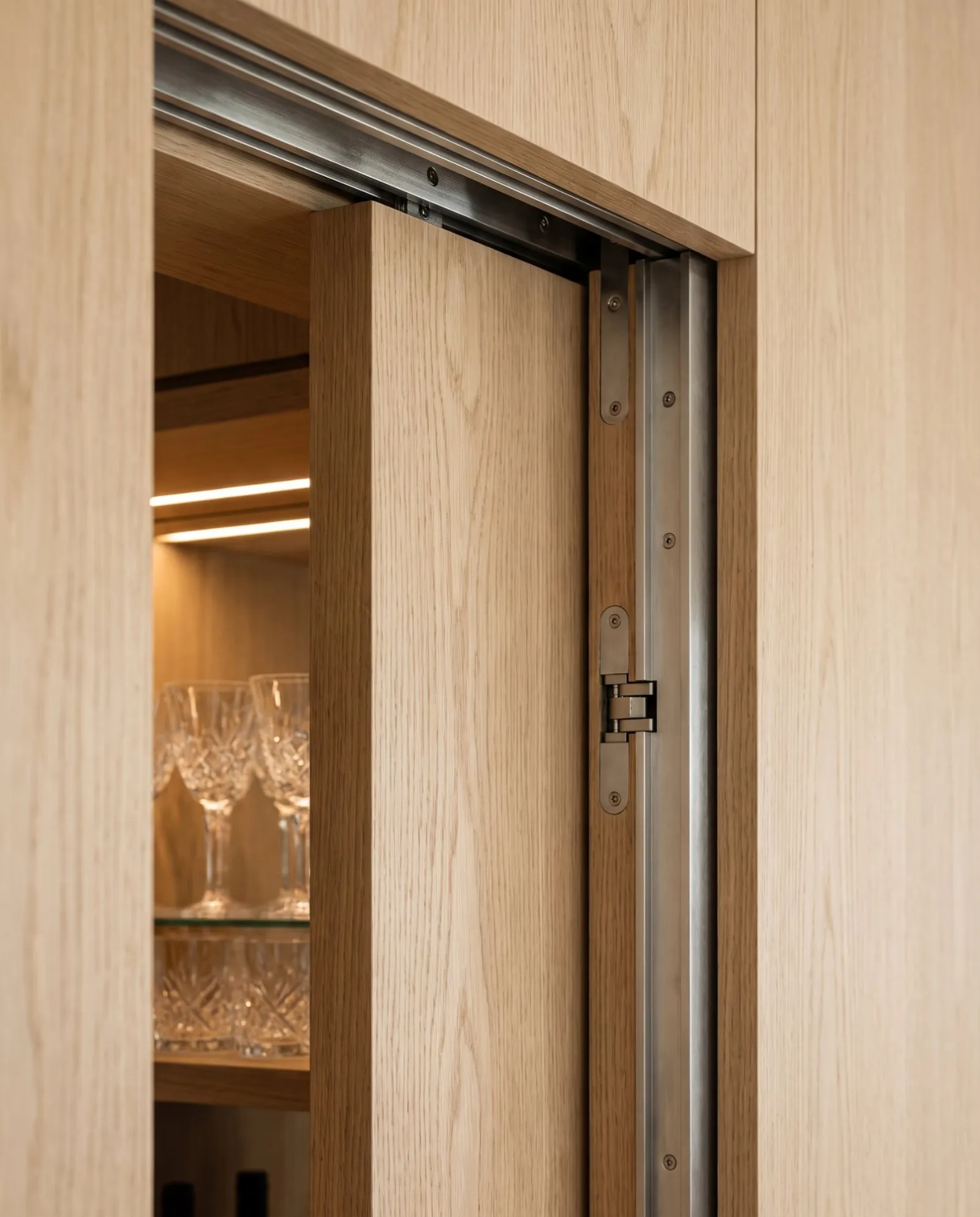 A flush oak door sliding into its pocket on steel hardware