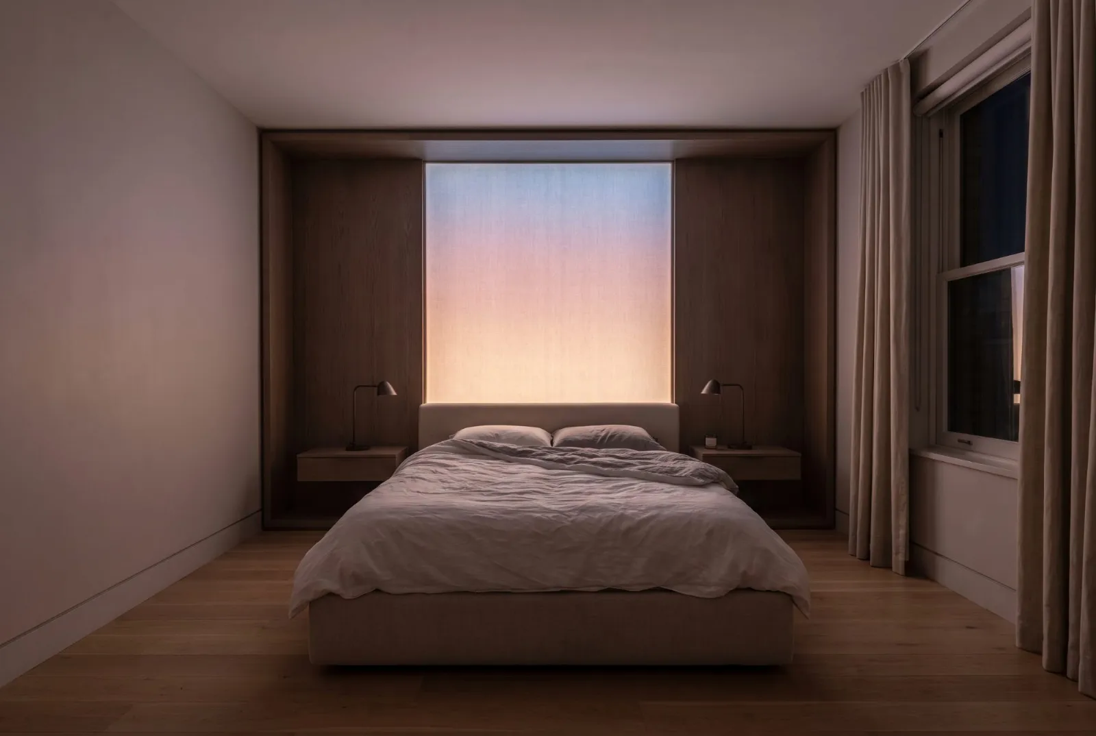 A bed in a smoked oak alcove with a glowing gradient panel above
